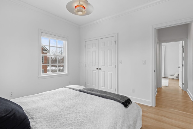 bedroom with light hardwood / wood-style flooring, ornamental molding, a closet, and ceiling fan