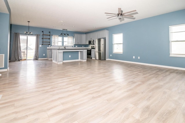 unfurnished living room with light hardwood / wood-style flooring, ceiling fan, and sink