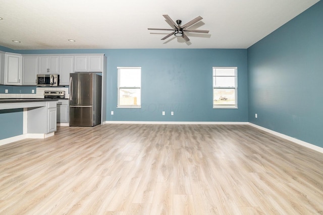 kitchen with a wealth of natural light, white cabinetry, light wood-type flooring, and appliances with stainless steel finishes