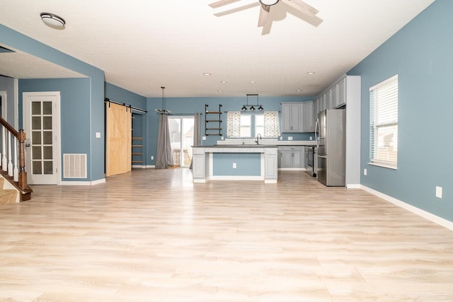 kitchen with a barn door, stainless steel fridge, plenty of natural light, and light wood-type flooring