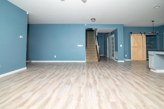 unfurnished living room with light wood-type flooring and a barn door