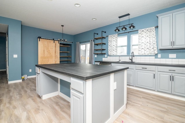 kitchen with a barn door, a kitchen island, pendant lighting, and light hardwood / wood-style floors