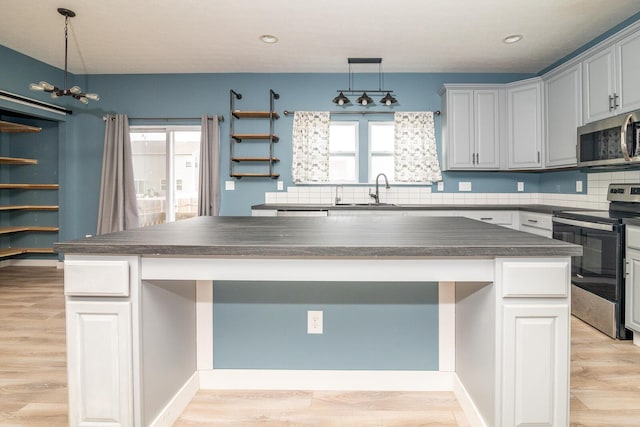 kitchen with plenty of natural light, a center island, light hardwood / wood-style flooring, and appliances with stainless steel finishes