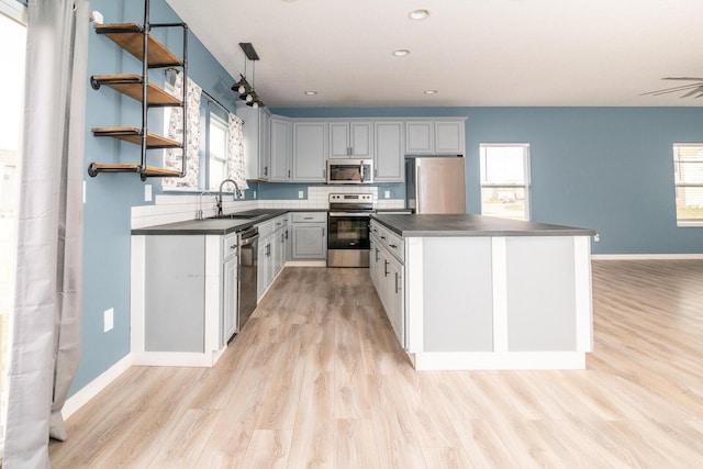 kitchen with sink, light hardwood / wood-style flooring, a healthy amount of sunlight, and appliances with stainless steel finishes