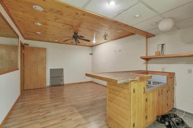 kitchen with ceiling fan, a kitchen bar, light wood-type flooring, and kitchen peninsula