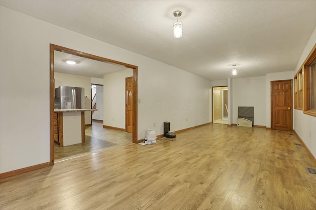 unfurnished living room featuring a textured ceiling and light hardwood / wood-style flooring