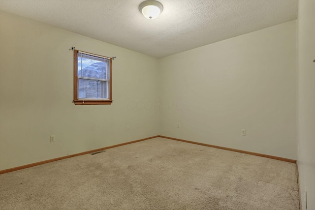 spare room featuring light carpet and a textured ceiling