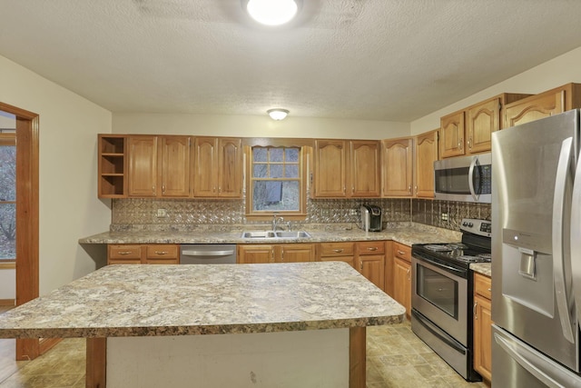 kitchen with sink, a center island, backsplash, a textured ceiling, and appliances with stainless steel finishes