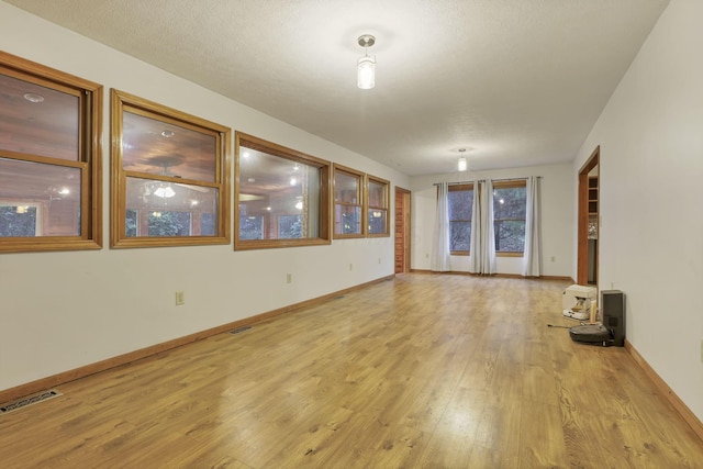 unfurnished living room with light hardwood / wood-style floors and a textured ceiling