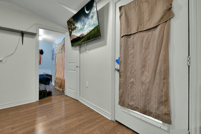 hallway with light hardwood / wood-style floors and vaulted ceiling