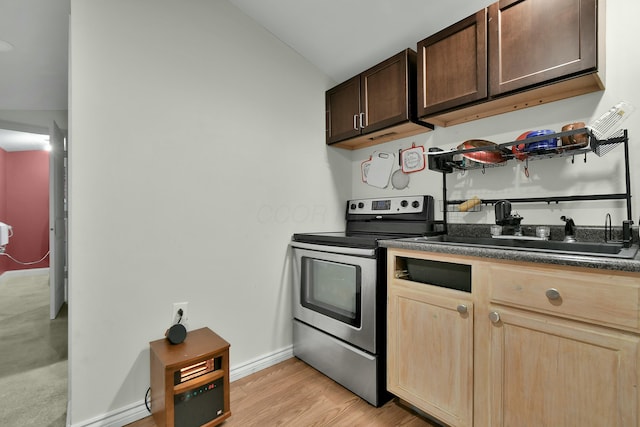 kitchen featuring lofted ceiling, light hardwood / wood-style floors, stainless steel range with electric cooktop, and sink