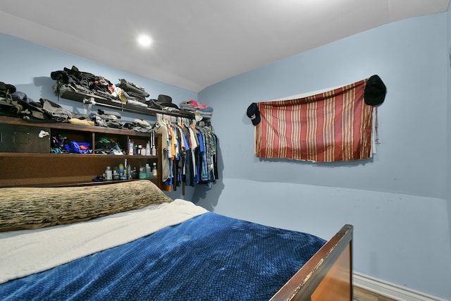 bedroom featuring vaulted ceiling, wood-type flooring, and a closet