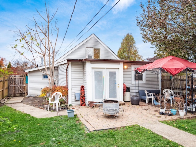 rear view of house featuring a yard, a patio, and a fire pit