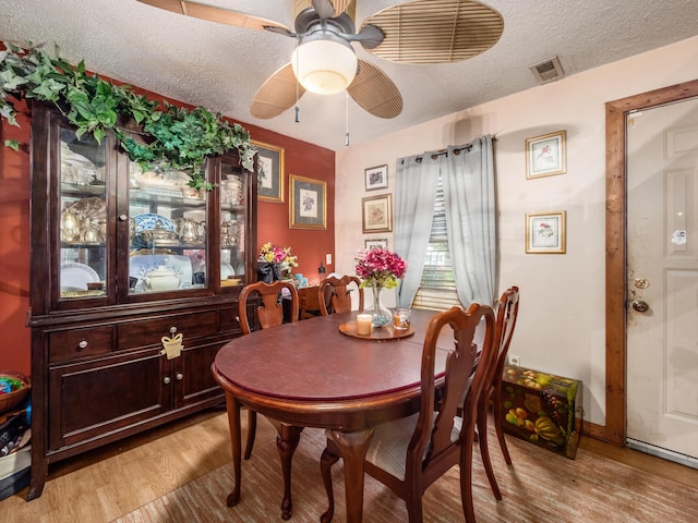 dining space featuring ceiling fan, light hardwood / wood-style floors, and a textured ceiling