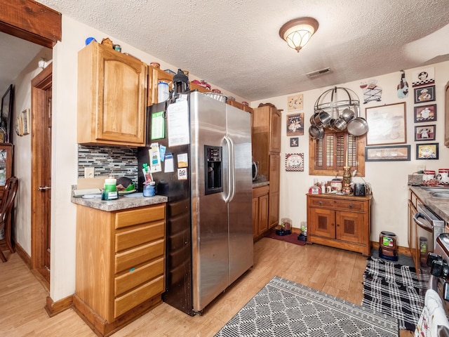 kitchen featuring backsplash, a textured ceiling, light hardwood / wood-style floors, and stainless steel refrigerator with ice dispenser