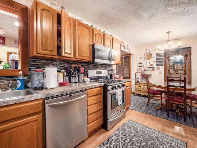 kitchen featuring an inviting chandelier, hanging light fixtures, a textured ceiling, light hardwood / wood-style floors, and stainless steel appliances