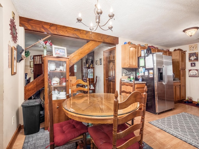 dining room with a textured ceiling, light hardwood / wood-style flooring, and a notable chandelier