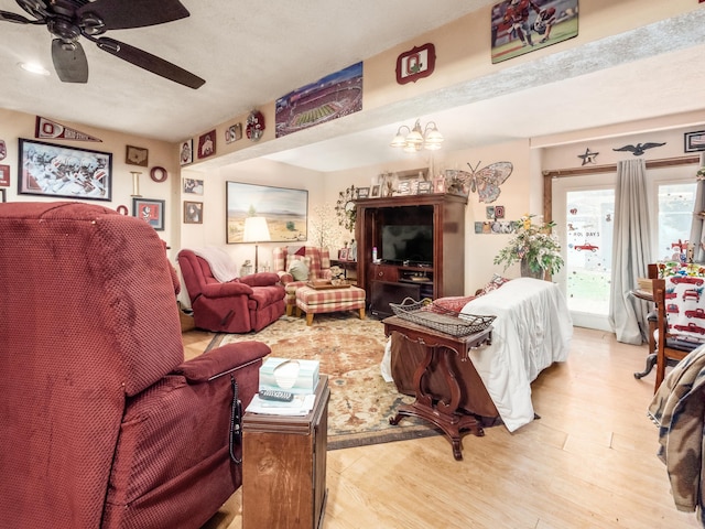 living room featuring light hardwood / wood-style flooring and ceiling fan with notable chandelier