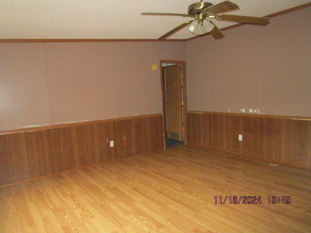 spare room featuring wood-type flooring, crown molding, and lofted ceiling