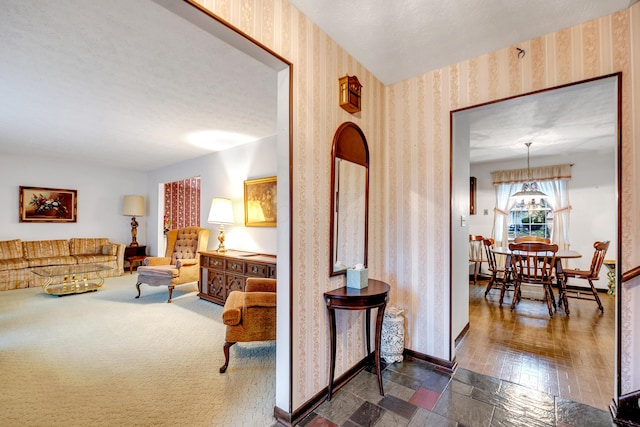 hall with a textured ceiling, dark hardwood / wood-style floors, and an inviting chandelier