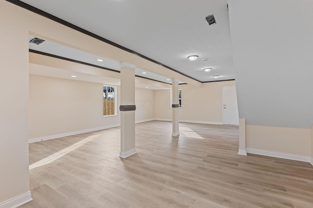 basement with light hardwood / wood-style floors and ornamental molding