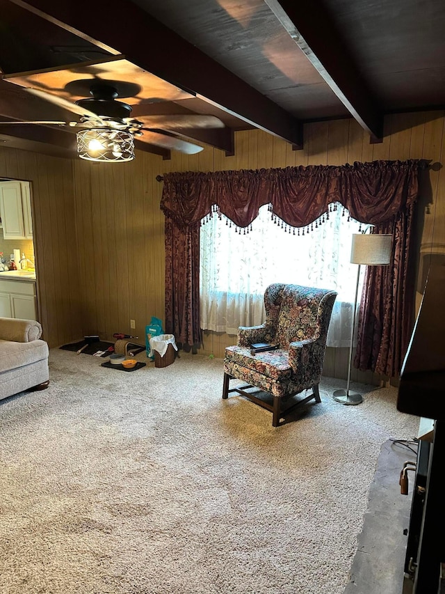 sitting room with carpet flooring, beam ceiling, ceiling fan, and wood walls