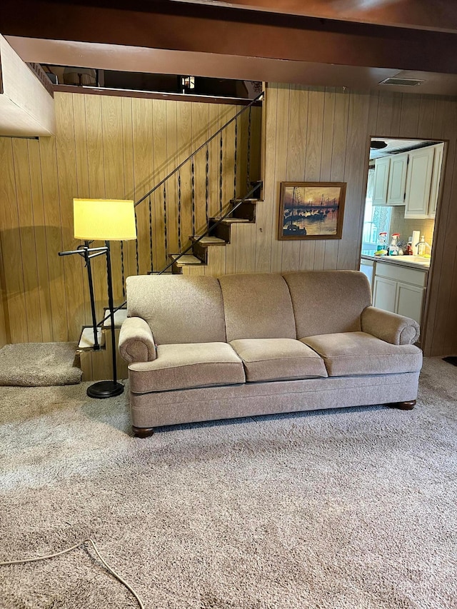 carpeted living room with wood walls and beam ceiling