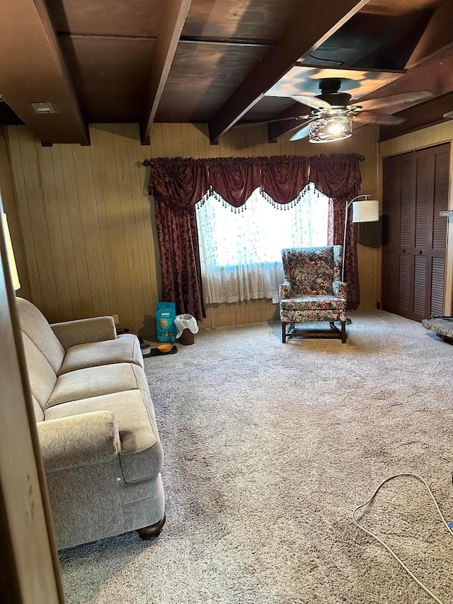 sitting room with ceiling fan, wooden walls, beam ceiling, wooden ceiling, and carpet floors