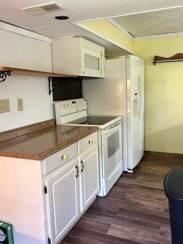 kitchen featuring white cabinets, dark hardwood / wood-style flooring, white appliances, and wooden walls