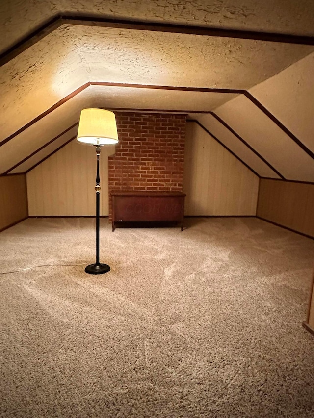 bonus room featuring wood walls, light carpet, and vaulted ceiling