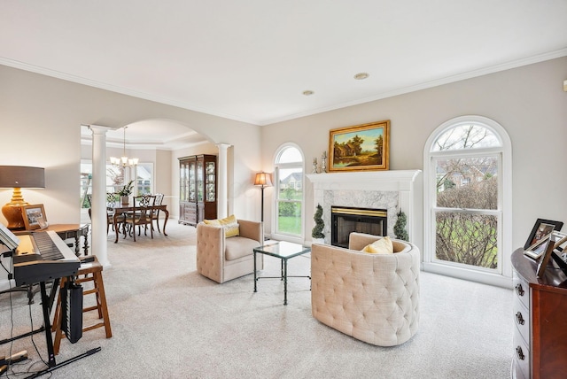 carpeted living room featuring a premium fireplace, crown molding, a wealth of natural light, and decorative columns