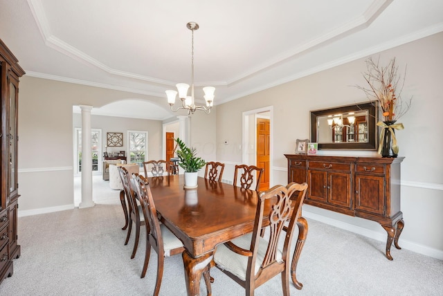 carpeted dining area featuring a raised ceiling, ornate columns, crown molding, and a chandelier