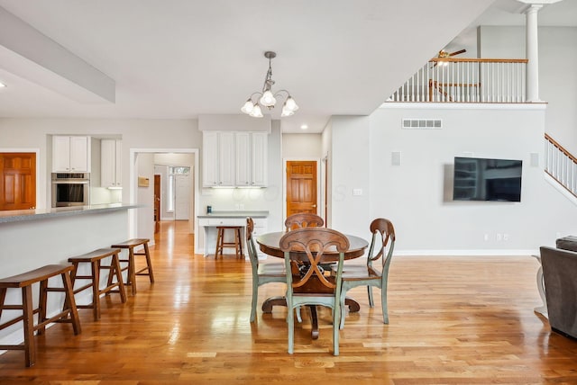 dining area featuring ceiling fan with notable chandelier and light hardwood / wood-style floors