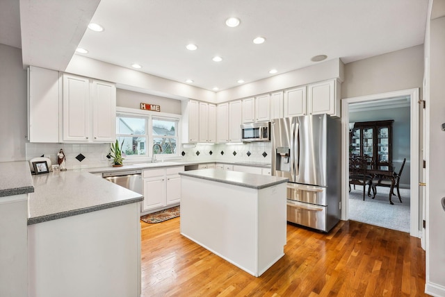 kitchen with white cabinetry, sink, stainless steel appliances, tasteful backsplash, and wood-type flooring