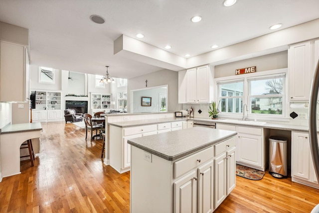 kitchen with kitchen peninsula, sink, a kitchen island, and light hardwood / wood-style floors