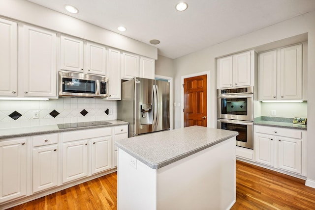 kitchen with stainless steel appliances, light hardwood / wood-style flooring, and white cabinetry