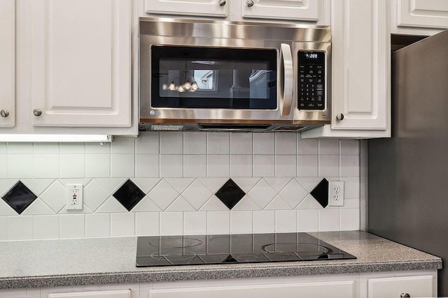 kitchen with stainless steel appliances, white cabinetry, and tasteful backsplash