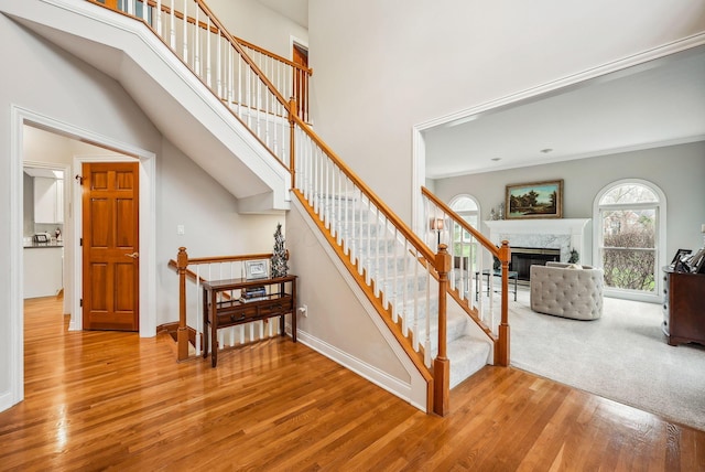 stairs with hardwood / wood-style flooring and a high end fireplace