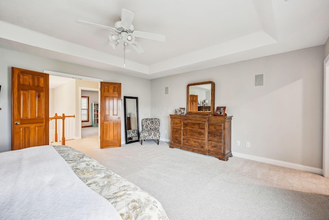 carpeted bedroom with a raised ceiling and ceiling fan