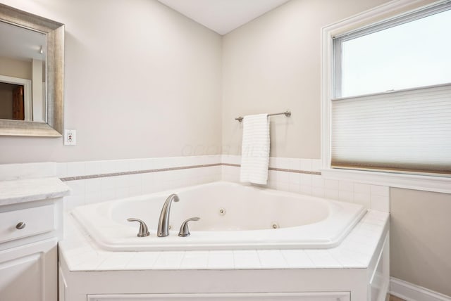 bathroom featuring vanity and a relaxing tiled tub