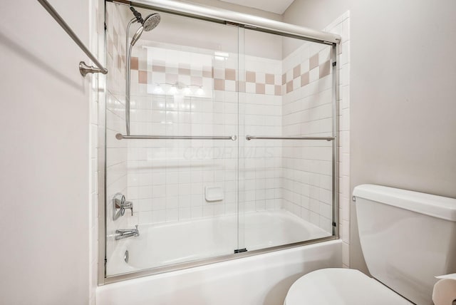 bathroom featuring toilet and bath / shower combo with glass door