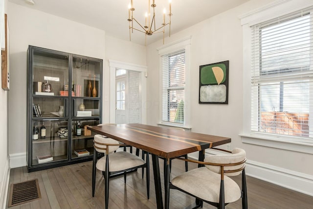 dining room featuring dark wood-type flooring, a wealth of natural light, and an inviting chandelier