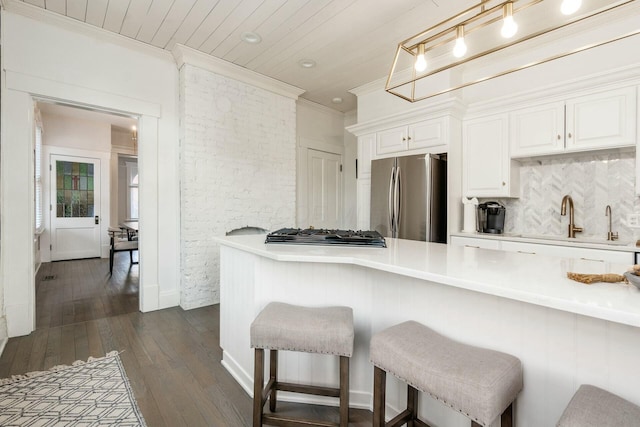 kitchen featuring stainless steel appliances, dark hardwood / wood-style flooring, kitchen peninsula, a kitchen bar, and white cabinets