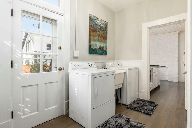 laundry room with hardwood / wood-style floors, separate washer and dryer, and brick wall