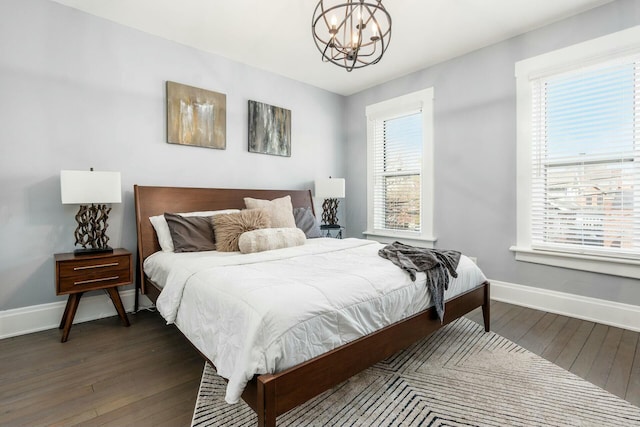 bedroom featuring multiple windows, dark wood-type flooring, and a notable chandelier