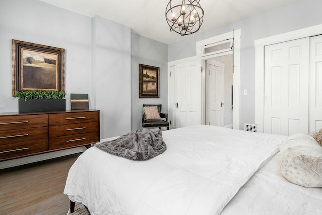 bedroom with dark wood-type flooring and a notable chandelier