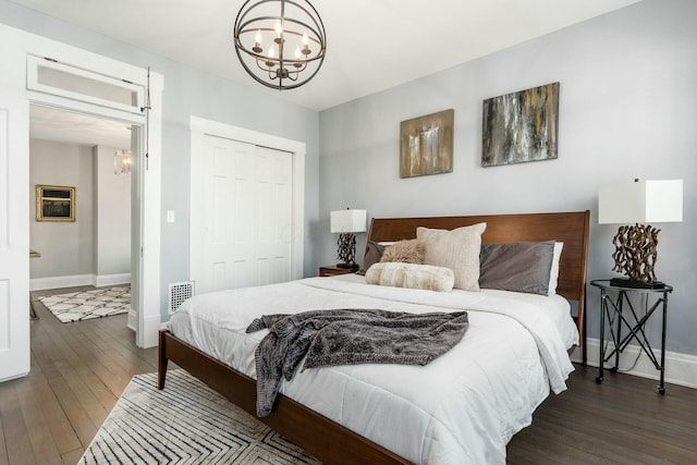 bedroom with dark hardwood / wood-style flooring, a closet, and an inviting chandelier