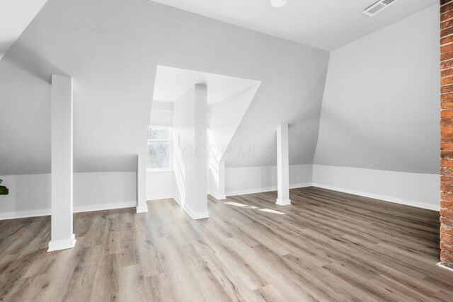 additional living space with light wood-type flooring and vaulted ceiling