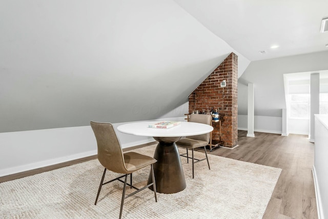 dining room with lofted ceiling and light wood-type flooring