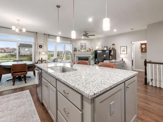 kitchen featuring decorative light fixtures, dark hardwood / wood-style flooring, an island with sink, and sink